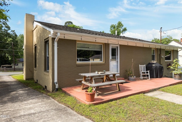 back of property with a chimney, a patio area, and brick siding