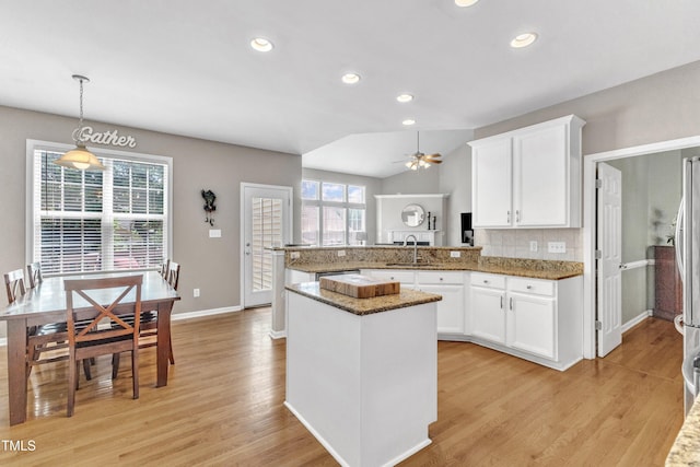 kitchen with a sink, a peninsula, healthy amount of natural light, stone counters, and recessed lighting
