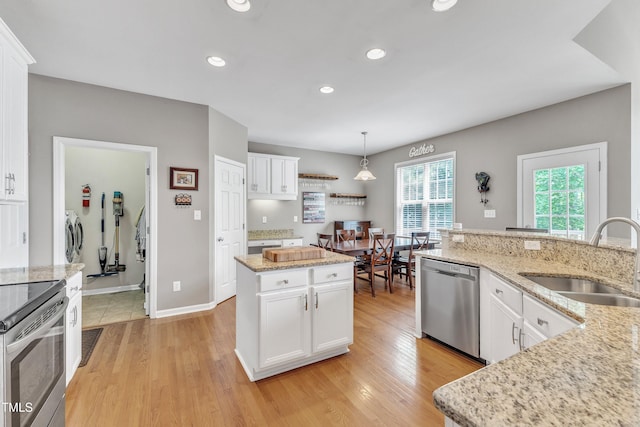 kitchen featuring stainless steel appliances, a sink, washer and dryer, recessed lighting, and light wood-type flooring