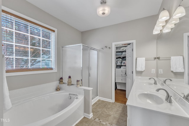 bathroom featuring a bath, a shower stall, tile patterned flooring, double vanity, and a spacious closet