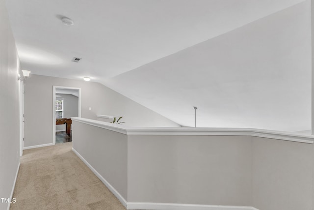 corridor featuring baseboards, carpet, and lofted ceiling