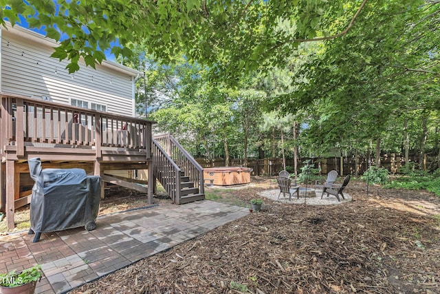 fenced backyard featuring a hot tub, a wooden deck, a patio, stairs, and an outdoor fire pit