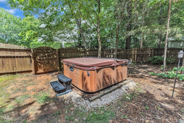 fenced backyard with a hot tub and a gate