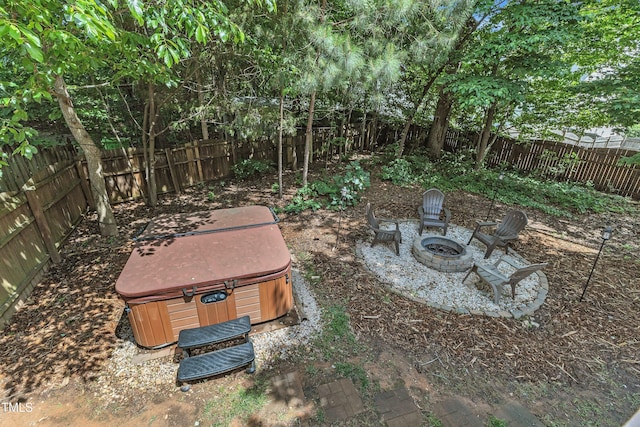 fenced backyard featuring a hot tub and a fire pit