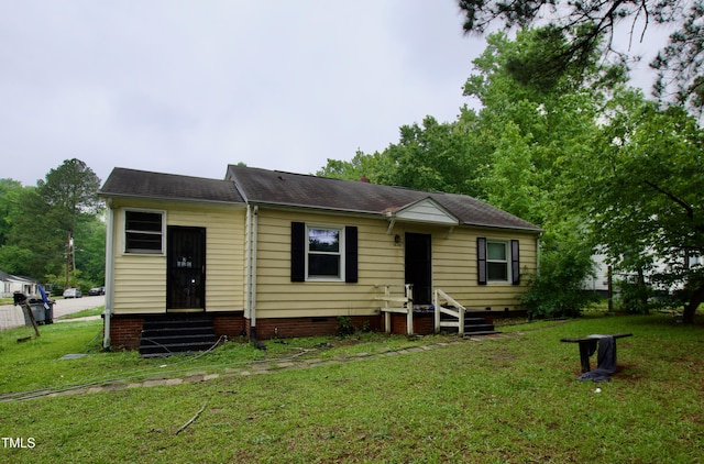 view of front of house with entry steps, a front yard, crawl space, and roof with shingles