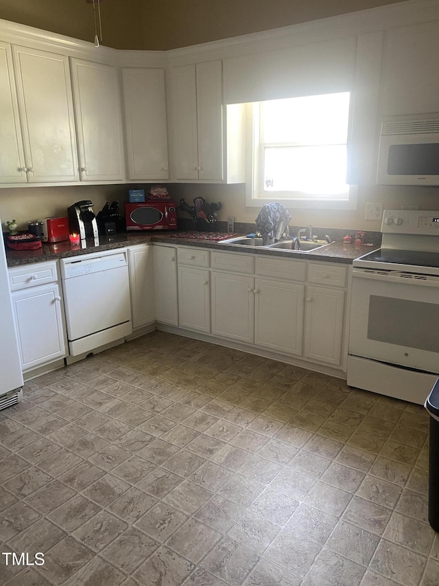 kitchen with white appliances, a sink, white cabinetry, and dark countertops