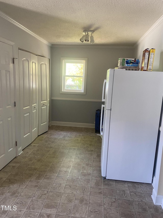 kitchen featuring freestanding refrigerator, crown molding, a textured ceiling, and baseboards