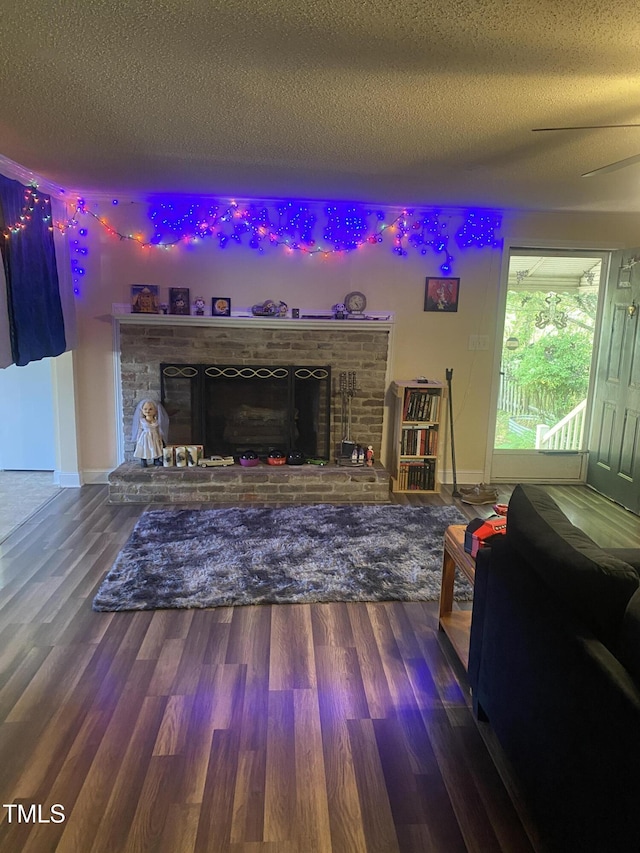 living area with a fireplace, a textured ceiling, wood finished floors, and baseboards