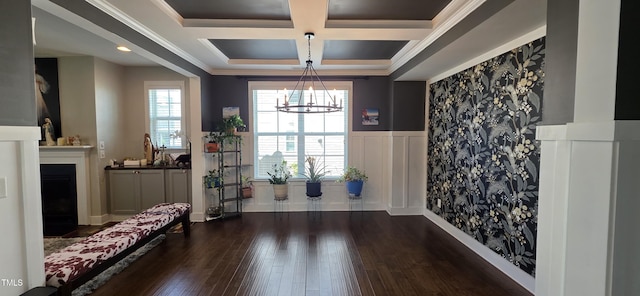interior space with coffered ceiling, dark wood-style floors, a wainscoted wall, a chandelier, and crown molding