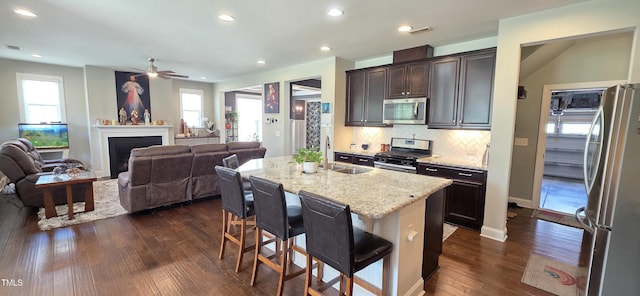kitchen featuring stainless steel appliances, dark wood finished floors, a sink, a breakfast bar area, and ceiling fan
