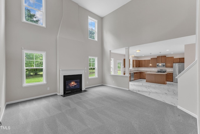 5025 Stonewood Pines Dr, Knightdale, NC 27545 - unfurnished living room featuring baseboards, a high ceiling, light colored carpet, and a fireplace with flush hearth