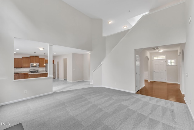 5025 Stonewood Pines Dr, Knightdale, NC 27545 - unfurnished living room with light carpet, a high ceiling, baseboards, and recessed lighting