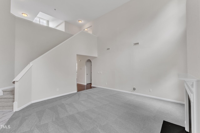 5025 Stonewood Pines Dr, Knightdale, NC 27545 - unfurnished living room with a high ceiling, carpet, stairway, baseboards, and arched walkways