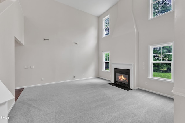 5025 Stonewood Pines Dr, Knightdale, NC 27545 - unfurnished living room featuring a towering ceiling, carpet floors, healthy amount of natural light, and a fireplace with flush hearth