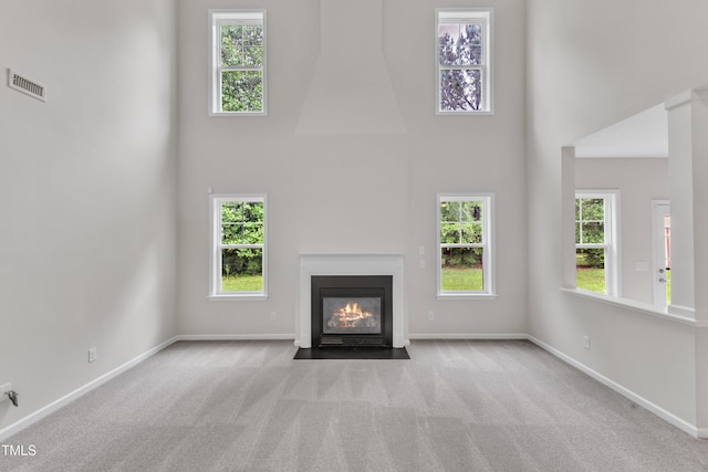 5025 Stonewood Pines Dr, Knightdale, NC 27545 - unfurnished living room featuring a towering ceiling, carpet floors, a fireplace with flush hearth, and baseboards