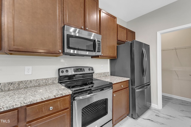 5025 Stonewood Pines Dr, Knightdale, NC 27545 - kitchen featuring stainless steel appliances, light marble finish flooring, brown cabinets, baseboards, and light stone counters