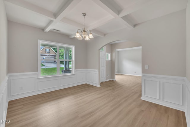 5025 Stonewood Pines Dr, Knightdale, NC 27545 - empty room with coffered ceiling, arched walkways, a chandelier, healthy amount of natural light, and a wainscoted wall