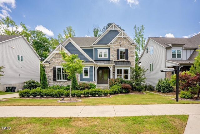 craftsman-style home featuring stone siding, a front lawn, and a standing seam roof