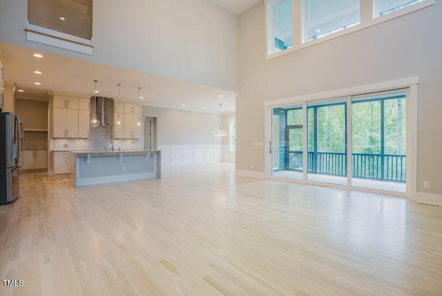 unfurnished living room with a towering ceiling and light wood finished floors