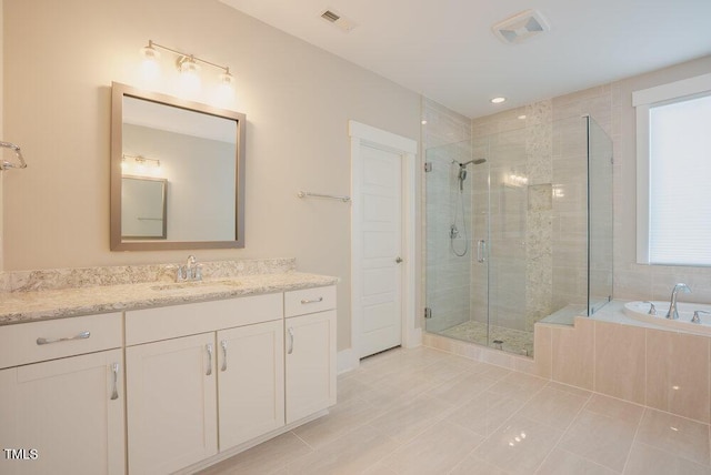 bathroom featuring a stall shower, vanity, a relaxing tiled tub, and tile patterned floors
