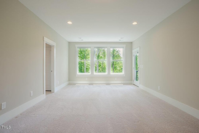 spare room featuring light carpet, recessed lighting, and baseboards