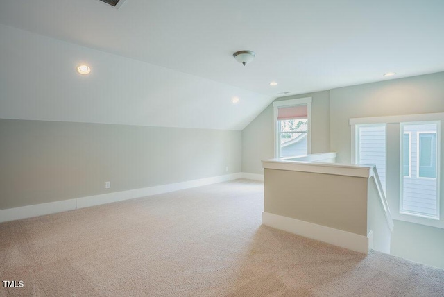 additional living space featuring light colored carpet, lofted ceiling, recessed lighting, and baseboards