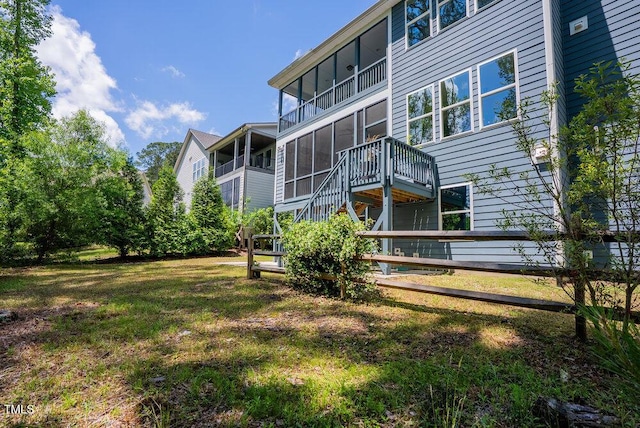 back of property with a yard, stairway, and a sunroom