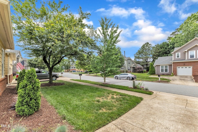 view of green lawn featuring a residential view and concrete driveway