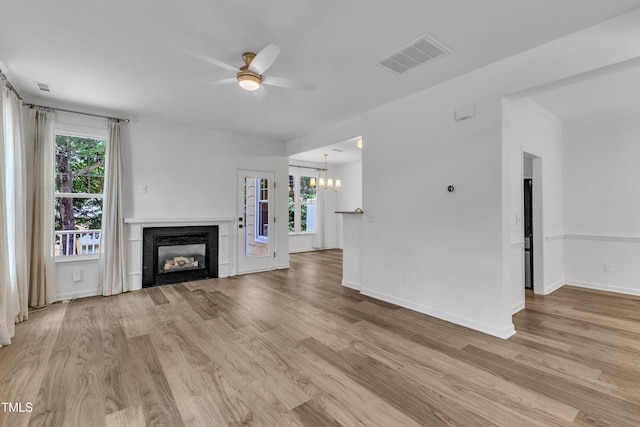 unfurnished living room featuring a ceiling fan, light wood-style floors, a glass covered fireplace, and plenty of natural light