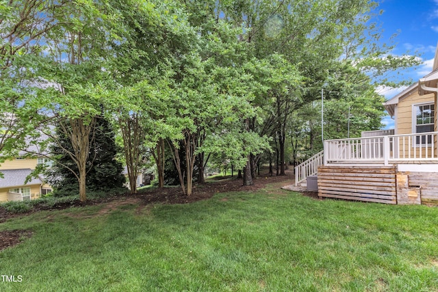 view of grassy yard featuring stairs and a wooden deck