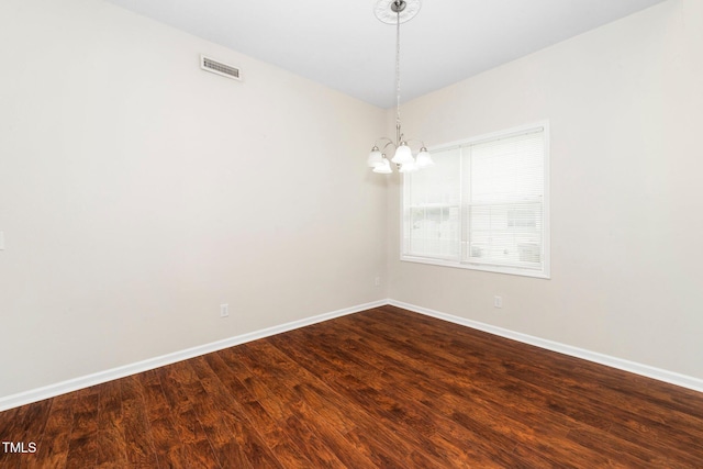 unfurnished room with a chandelier, dark wood-style floors, and baseboards