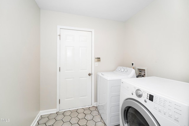 laundry area featuring washer and clothes dryer, baseboards, and light tile patterned floors