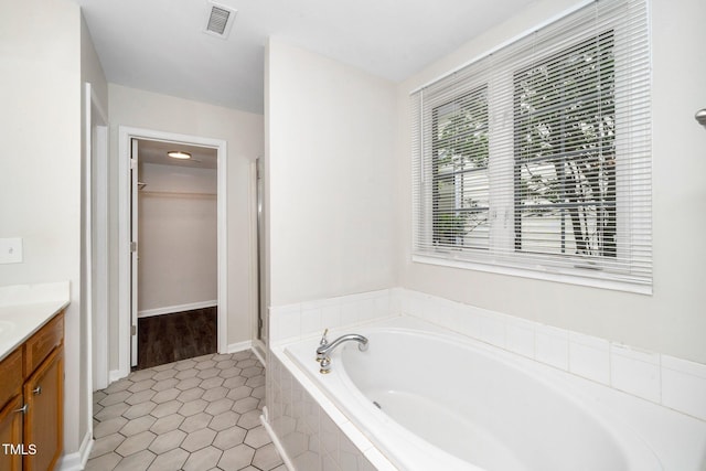 full bath featuring vanity, a bath, tile patterned floors, and a walk in closet