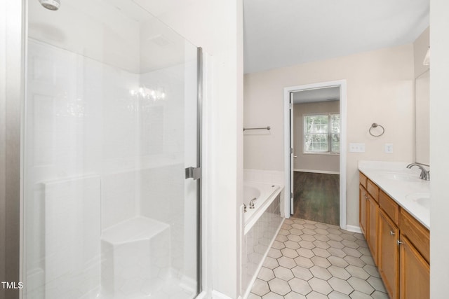 bathroom featuring a garden tub, a stall shower, double vanity, tile patterned flooring, and baseboards