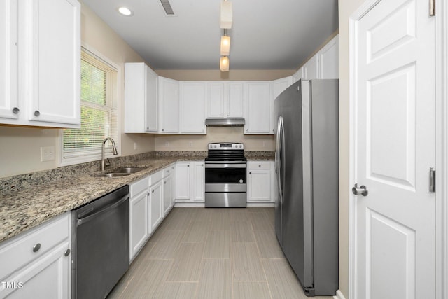 kitchen featuring appliances with stainless steel finishes, under cabinet range hood, a sink, white cabinets, and recessed lighting