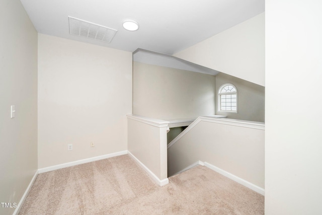 hallway with an upstairs landing, carpet, and baseboards