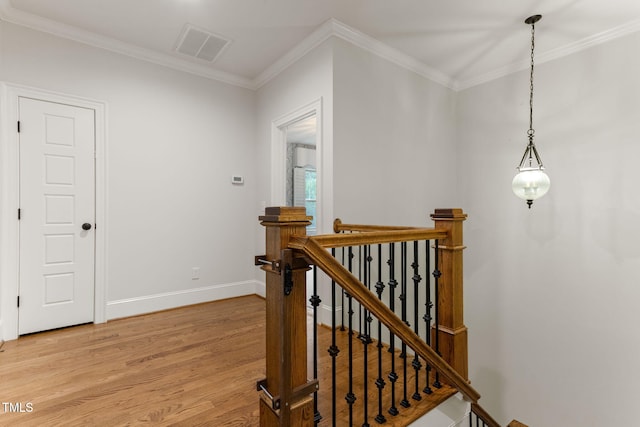 hall with an upstairs landing, light wood-type flooring, crown molding, and baseboards