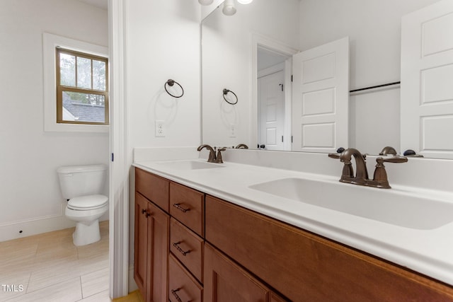 bathroom featuring toilet, double vanity, baseboards, and tile patterned flooring