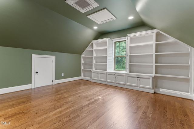 bonus room featuring vaulted ceiling, light wood finished floors, baseboards, built in shelves, and recessed lighting