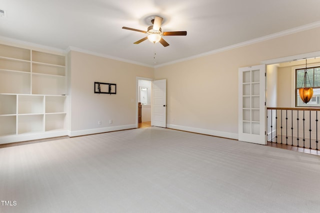 unfurnished room featuring a ceiling fan, crown molding, baseboards, carpet flooring, and built in features