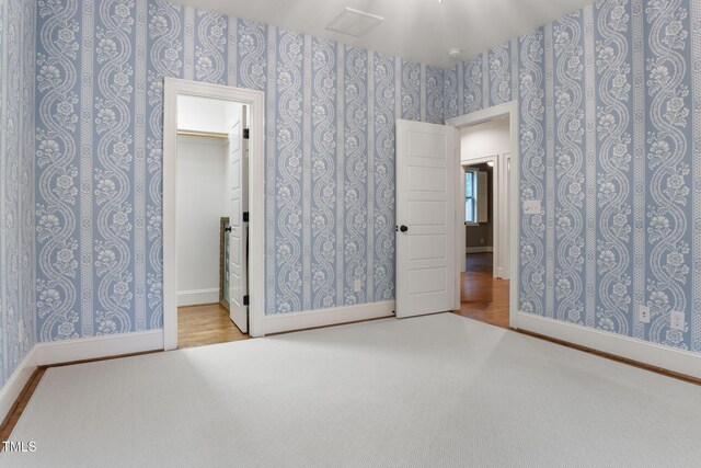 unfurnished bedroom featuring wallpapered walls, baseboards, and carpet flooring