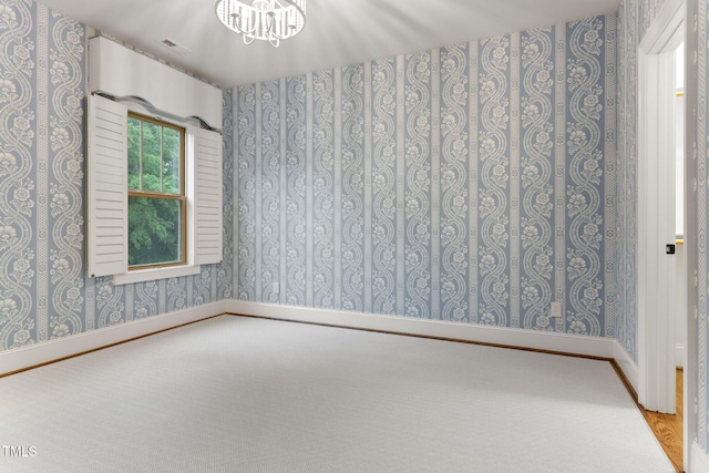 unfurnished room featuring wallpapered walls, a chandelier, baseboards, and carpet