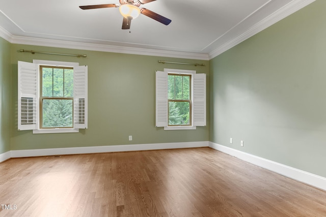 unfurnished room featuring crown molding, healthy amount of natural light, wood finished floors, a ceiling fan, and baseboards