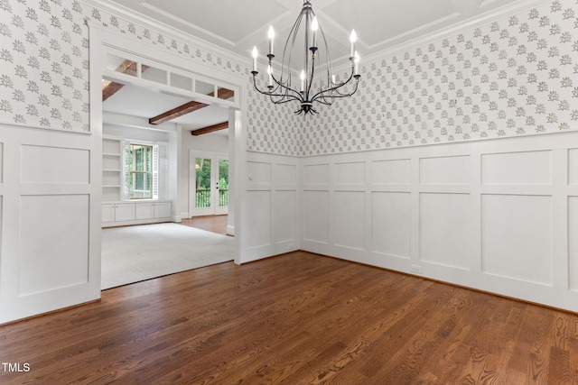 unfurnished dining area with a decorative wall, a chandelier, wallpapered walls, dark wood-style floors, and ornamental molding