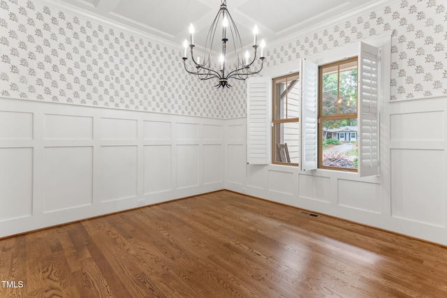 unfurnished dining area with a decorative wall, a chandelier, wallpapered walls, ornamental molding, and wainscoting