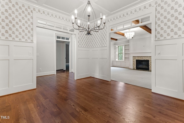 unfurnished dining area featuring a chandelier, a decorative wall, wallpapered walls, wainscoting, and dark wood-style floors