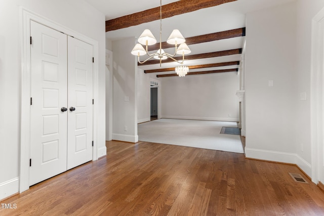 unfurnished dining area featuring a chandelier, beam ceiling, baseboards, and wood finished floors