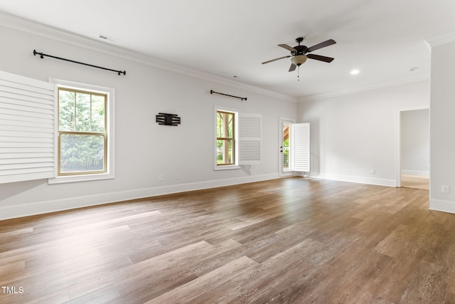 unfurnished room with healthy amount of natural light, a ceiling fan, crown molding, wood finished floors, and baseboards