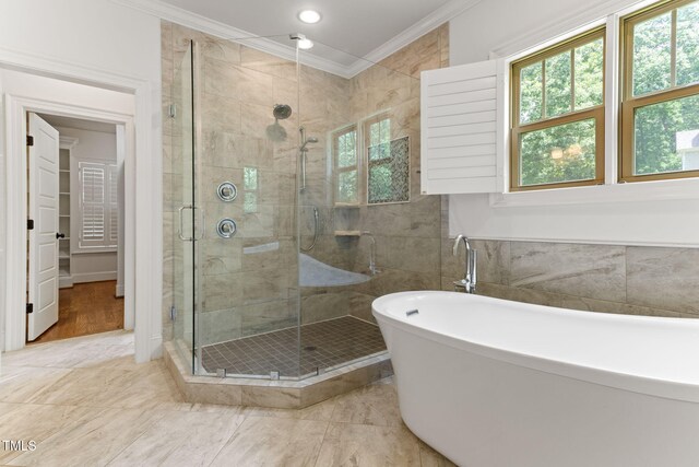 bathroom featuring ornamental molding, a stall shower, a freestanding bath, and recessed lighting