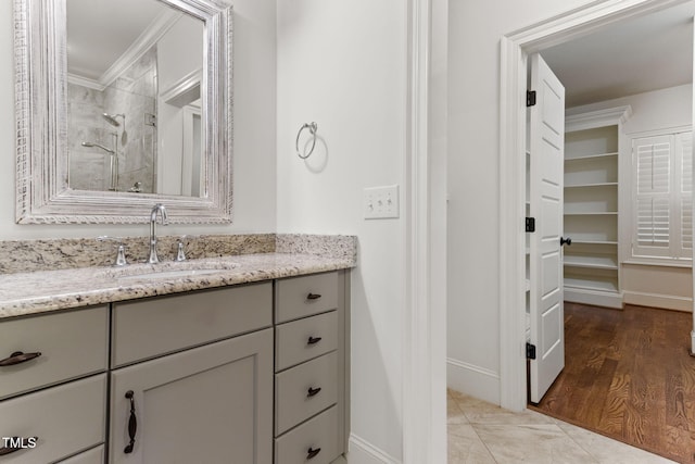 bathroom featuring a stall shower, baseboards, vanity, and crown molding